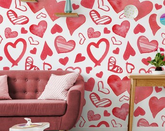 May include: A red sofa with a pink and white patterned pillow sits in front of a white wall with a red heart pattern. The wall is decorated with red hearts of various sizes and shapes, some with white stripes.