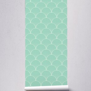 May include: A roll of teal blue wallpaper with a white geometric pattern of overlapping fan shapes.