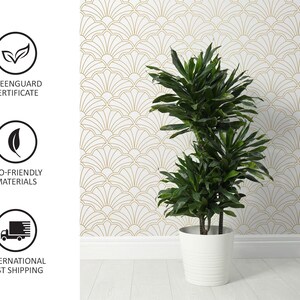 May include: A green plant in a white pot with a gold and white geometric patterned wallpaper in the background.