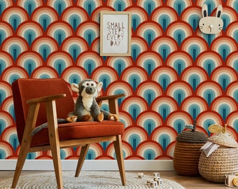 Può includere: Una poltrona rossa con gambe in legno si trova di fronte a un muro con una carta da parati in stile retrò con un motivo di archi arancioni, rossi e blu. Una scimmia di peluche è seduta sulla sedia. Una citazione motivazionale incorniciata dice "Piccoli passi ogni giorno".