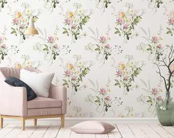 May include: A pink armchair with a white pillow and a blue throw pillow sits in front of a white wall with a floral wallpaper pattern. A green vase with a bare branch sits on the floor next to the chair.