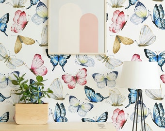 May include: A white wall with a butterfly wallpaper pattern. The wallpaper features butterflies in shades of blue, pink, and brown. A wooden cabinet with a light wood finish is in front of the wall. The cabinet has a shelf and a door with a geometric design. A potted plant is on the cabinet. A floor lamp with a white shade is next to the cabinet.