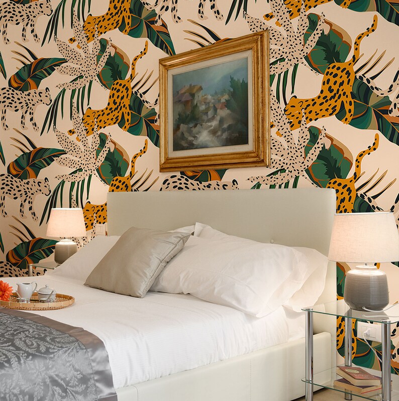 Peut inclure: Une chambre &agrave; coucher avec une t&ecirc;te de lit blanche et une literie blanche. Les murs sont recouverts d'un papier peint &agrave; motifs de feuilles vertes et de l&eacute;opards orange et noirs. Il y a un tableau au-dessus de la t&ecirc;te de lit et deux lampes sur des tables de chevet.
