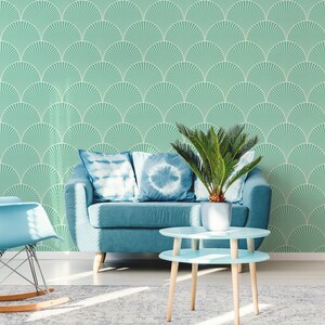 May include: A living room interior with a teal blue sofa, two blue throw pillows, a rocking chair, a potted plant, and a two-tiered light blue coffee table. The wall is covered in a teal green wallpaper with a white geometric pattern.