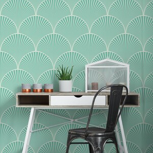 May include: A white desk with a black metal chair in front of it. The desk has a white drawer and a wooden top. The wall behind the desk is covered in a teal and white geometric wallpaper.