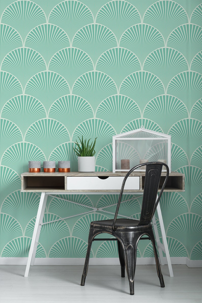May include: A white desk with a black metal chair in front of it. The desk has a white drawer and a wooden top. The wall behind the desk is covered in a teal and white geometric wallpaper.