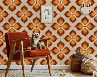 Può includere: Una carta da parati in stile retrò con un motivo ripetitivo di forme di fiori di colore arancione, marrone e crema. Una sedia in legno con un cuscino in velluto rosso si trova davanti alla carta da parati. Una scimmia di peluche è seduta sulla sedia. Una stampa incorniciata con il testo "Small steps every day" è appesa al muro.