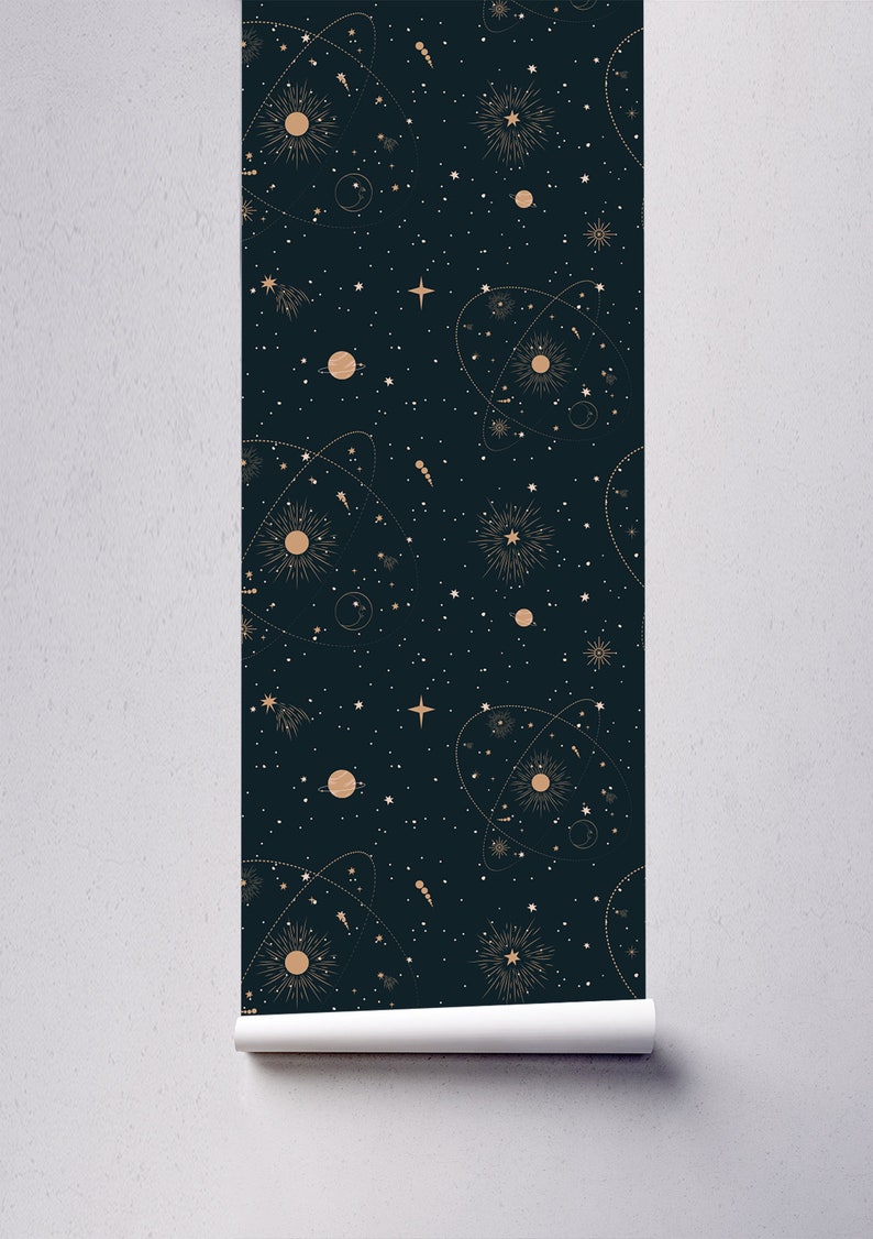 Op de afbeelding: Een donkerblauwe behang met een herhalend patroon van gouden sterren, planeten en zonnen. Het patroon doet denken aan een nachtelijke sterrenhemel.