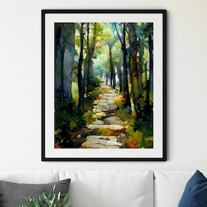 Puede incluir: Una pintura al agua enmarcada de un camino de piedra que serpentea a través de un bosque. El camino está bordeado de árboles y la luz brilla a través de las hojas. La pintura está en un marco negro y está colgada en una pared blanca.