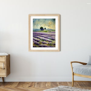 May include: A watercolor painting of a lavender field with a small tree in the distance. The sky is a light blue with white clouds. The painting is framed in a light wood frame.