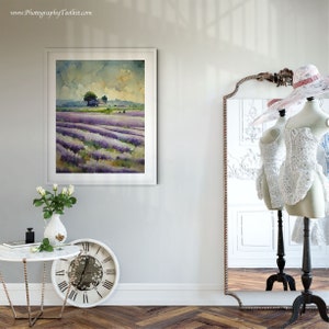 May include: A framed watercolor painting of a lavender field with a small tree in the distance. The painting is hanging on a white wall in a room with a mirror and a table with a vase of white roses.