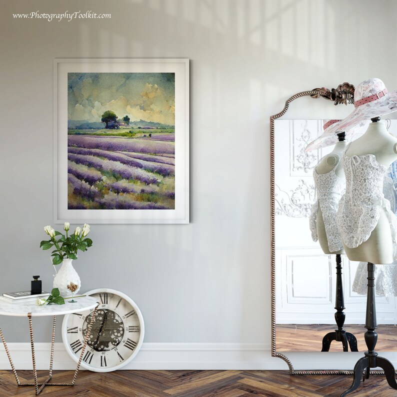 May include: A framed watercolor painting of a lavender field with a small tree in the distance. The painting is hanging on a white wall in a room with a mirror and a table with a vase of white roses.