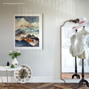 May include: A framed watercolor painting of a mountain range with blue, brown, and white hues. The painting is hanging on a white wall with a mirror and a clock in the foreground.