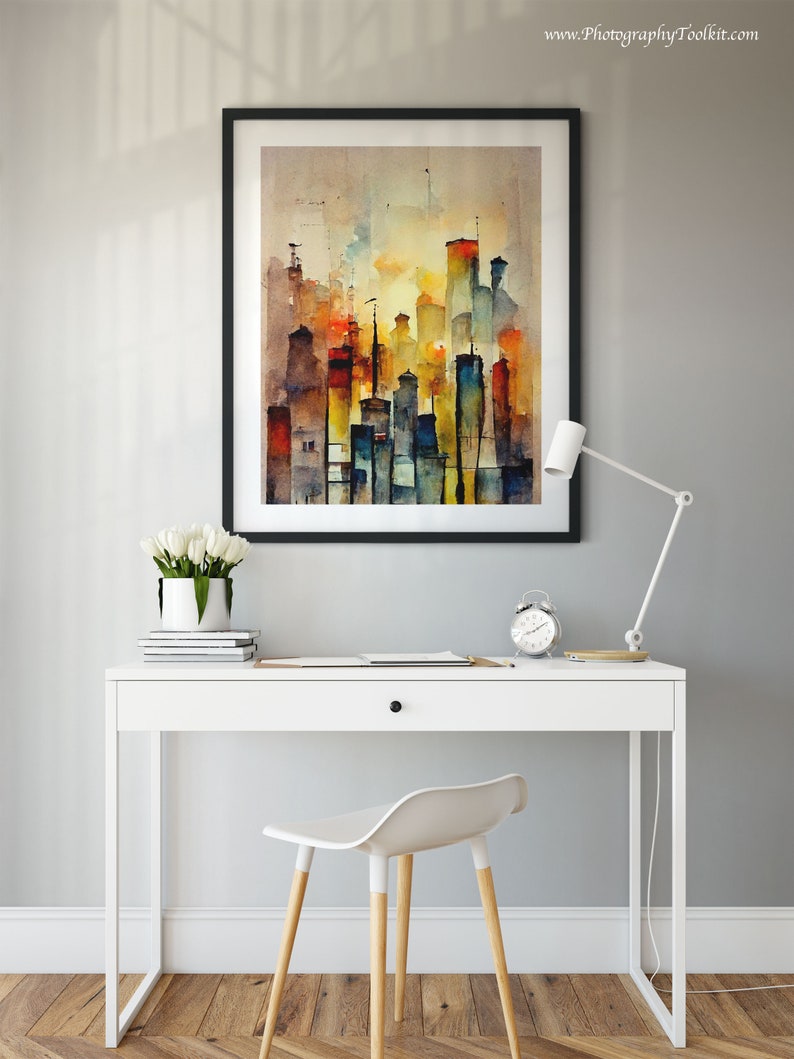 May include: A white desk with a drawer and a black frame picture of a watercolor painting of a city skyline. The desk has a white lamp and a white chair with wooden legs. The painting is on a light gray wall.