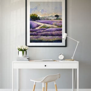 May include: A framed watercolor painting of a lavender field with a winding path leading through the field. The painting is hanging on a gray wall above a white desk with a white chair.