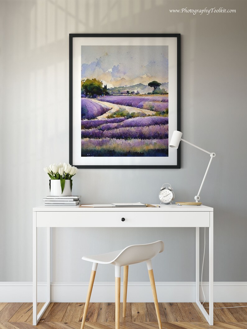 May include: A framed watercolor painting of a lavender field with a winding path leading through the field. The painting is hanging on a gray wall above a white desk with a white chair.