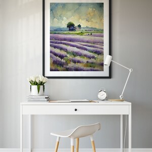 May include: A framed watercolor painting of a lavender field with a small house and trees in the distance. The painting is hanging on a gray wall above a white desk with a white chair and a white lamp.