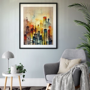 May include: A framed watercolor painting of a city skyline in shades of blue, yellow, orange, and red. The painting is hanging on a light gray wall above a gray armchair with a white throw blanket.