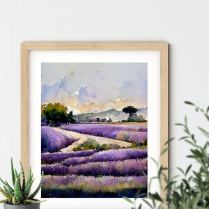 May include: A watercolor painting of a lavender field with a dirt road winding through it. The sky is a light blue with white clouds. There is a small tree on the right side of the painting.