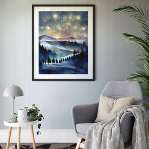 Pode incluir: Uma pintura em aquarela de um c&eacute;u noturno estrelado sobre uma cordilheira com uma floresta em primeiro plano. A pintura est&aacute; emoldurada em uma moldura preta e pendurada em uma parede azul clara.