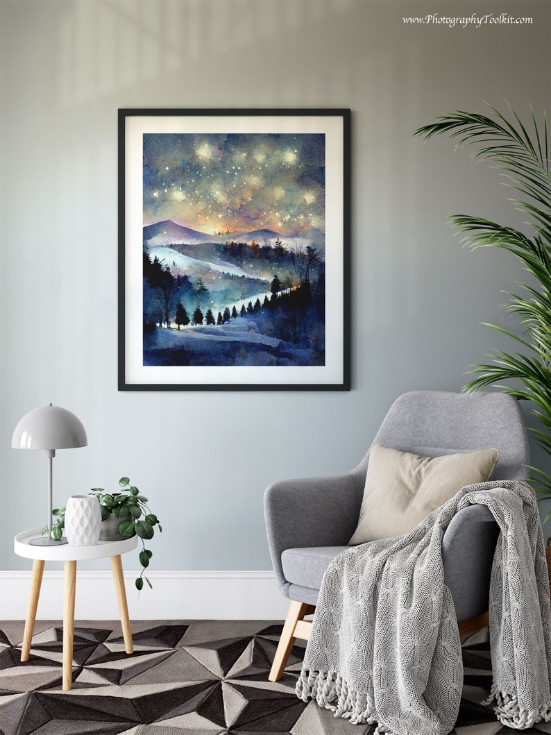 Pode incluir: Uma pintura em aquarela de um c&eacute;u noturno estrelado sobre uma cordilheira com uma floresta em primeiro plano. A pintura est&aacute; emoldurada em uma moldura preta e pendurada em uma parede azul clara.