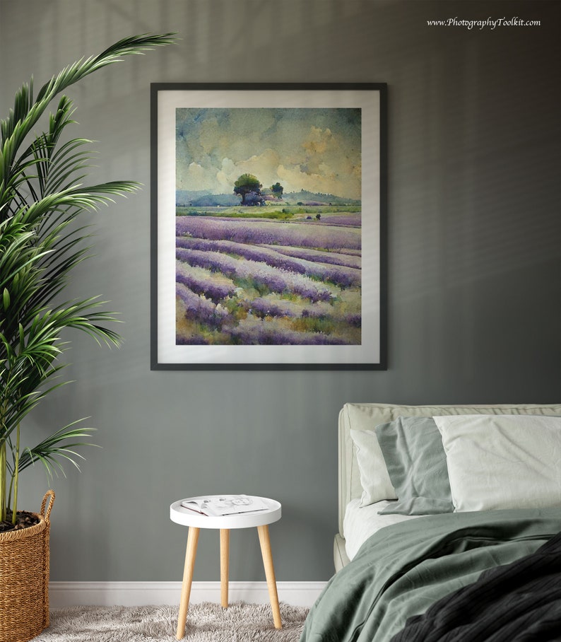 May include: A framed watercolor painting of a lavender field with a small cluster of trees in the distance. The painting is hanging on a gray wall above a white side table and a green bed.