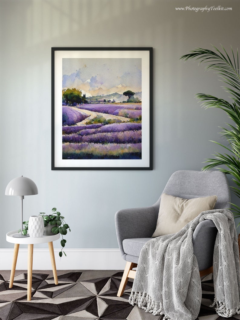 May include: A framed watercolor painting of a lavender field with a winding path leading to a small tree in the distance. The painting is hanging on a light gray wall above a gray armchair with a white throw blanket.