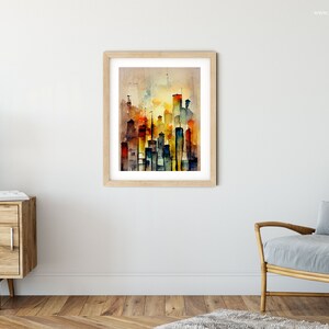 May include: A watercolor painting of a city skyline in shades of orange, yellow, blue, and green. The painting is framed in a light wood frame and is hanging on a white wall.