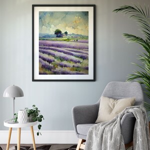 May include: A framed watercolor painting of a lavender field with a small cluster of trees in the distance. The painting is hanging on a light blue wall in a living room setting.