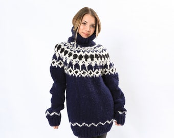 Peut inclure: Une femme portant un pull bleu et blanc à motifs avec un col roulé. Elle porte un legging noir et des bottes noires.