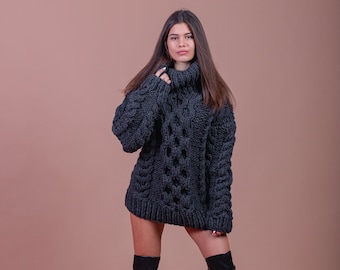May include: A woman wearing a gray chunky knit turtleneck sweater and black knee-high boots. The sweater has a cable knit pattern.