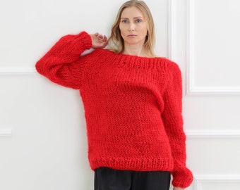 Könnte beinhalten: Ein roter, grob gestrickter Pullover mit lockerer Passform und langen Ärmeln. Der Pullover ist aus weichem, flauschigem Garn gefertigt.