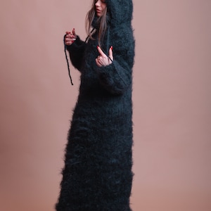 May include: A long, black, fuzzy hooded sweater dress. The sweater is made of a soft, fluffy material and has a loose fit.