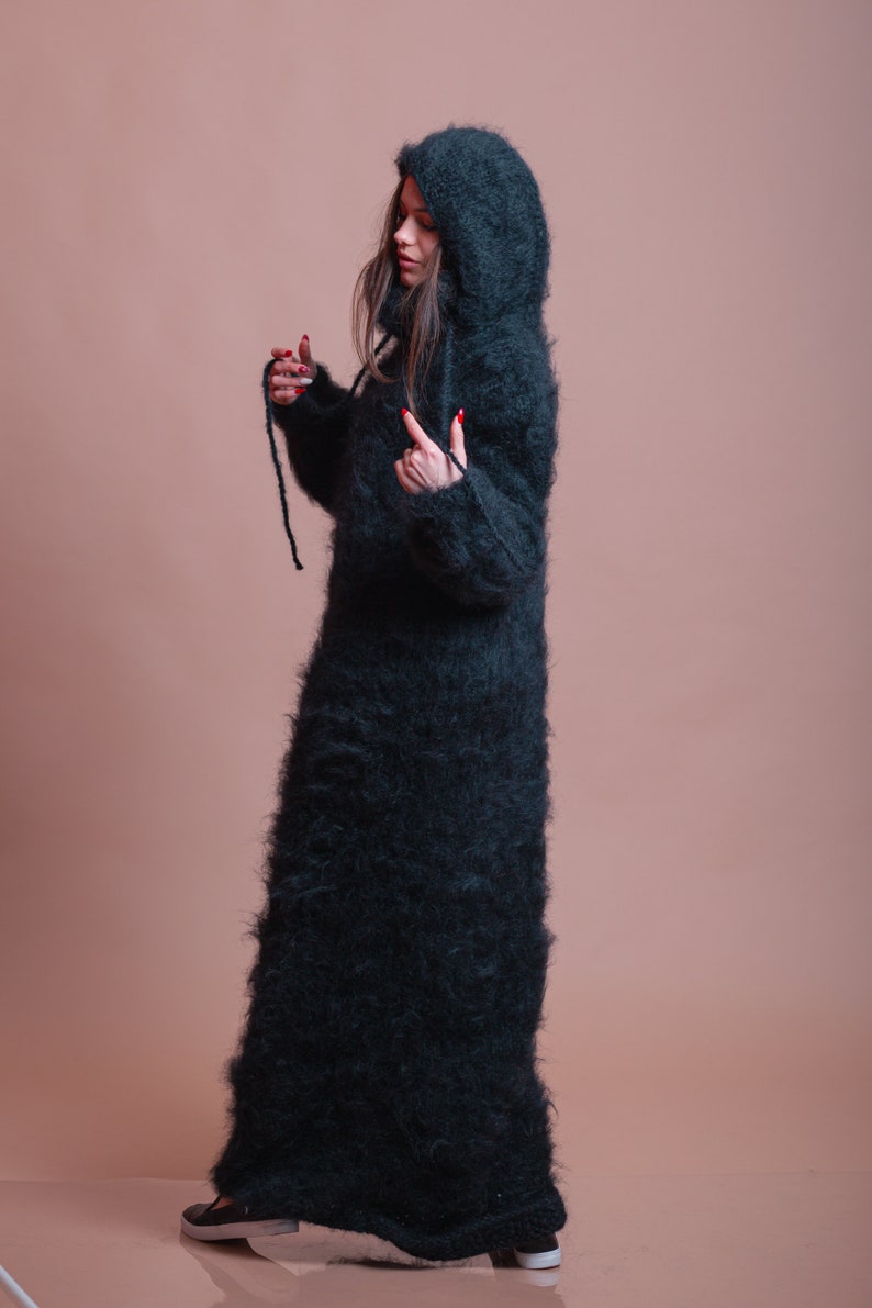 May include: A long, black, fuzzy hooded sweater dress. The sweater is made of a soft, fluffy material and has a loose fit.