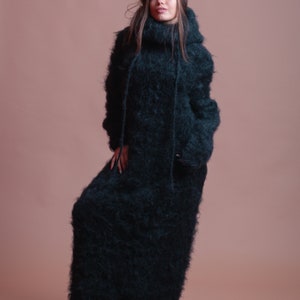 May include: A long, black, fuzzy sweater dress with a high neck and a hood.