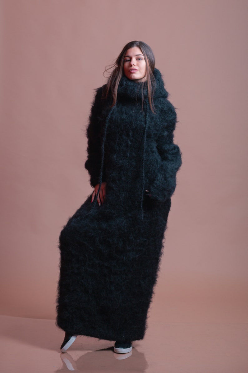 May include: A long, black, fuzzy sweater dress with a high neck and a hood.