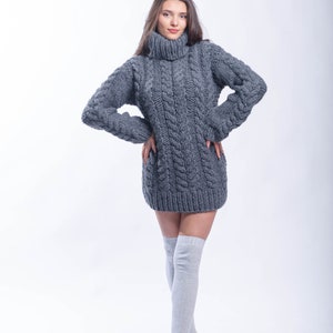 May include: A gray cable knit sweater dress with a turtleneck. The sweater is worn with gray knee-high socks.