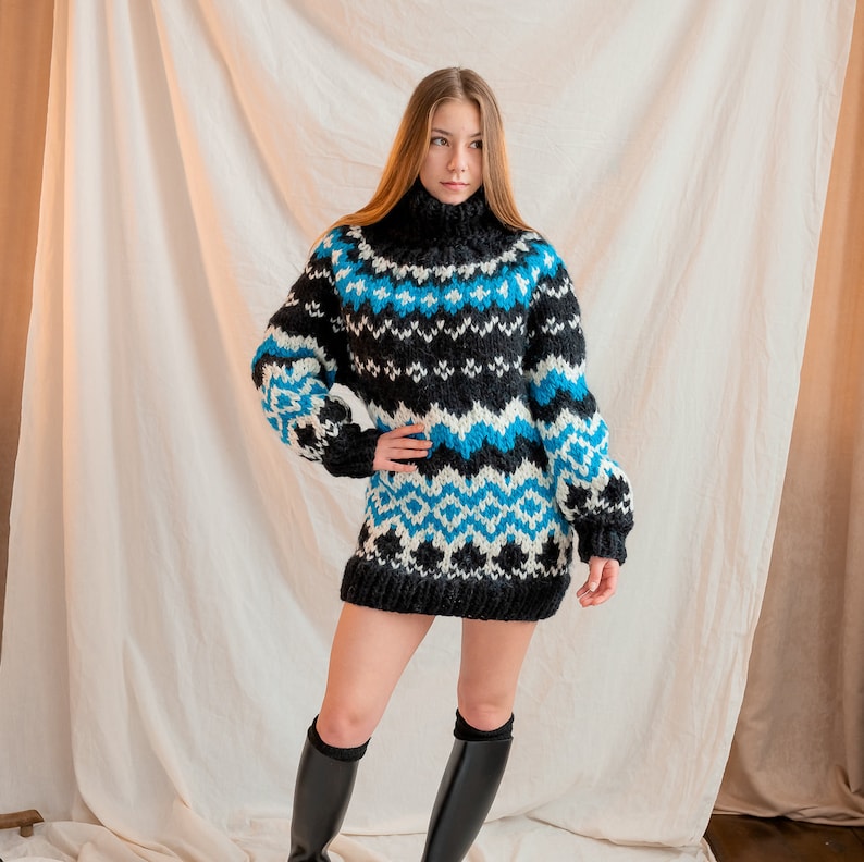 May include: A black and blue patterned sweater with a high neck and long sleeves. The sweater is made of a thick, fuzzy yarn and has a loose fit.