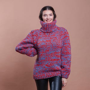 Puede incluir: Un suéter de cuello alto de punto grueso rojo y azul con un ajuste holgado.