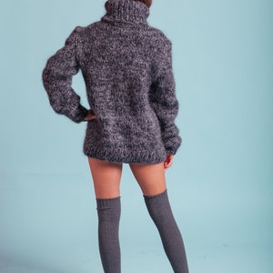 May include: A gray fuzzy turtleneck sweater with long sleeves and a high neckline. The sweater is worn with gray knee-high socks.