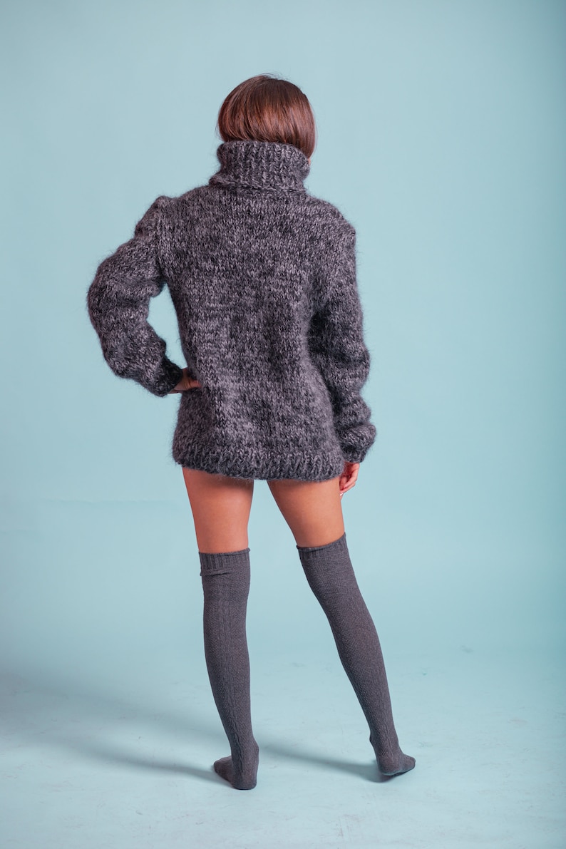 May include: A gray fuzzy turtleneck sweater with long sleeves and a high neckline. The sweater is worn with gray knee-high socks.