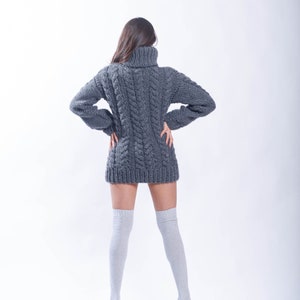 May include: A woman wearing a gray cable knit sweater dress and white knee-high socks.