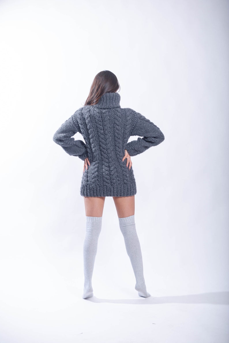 May include: A woman wearing a gray cable knit sweater dress and white knee-high socks.
