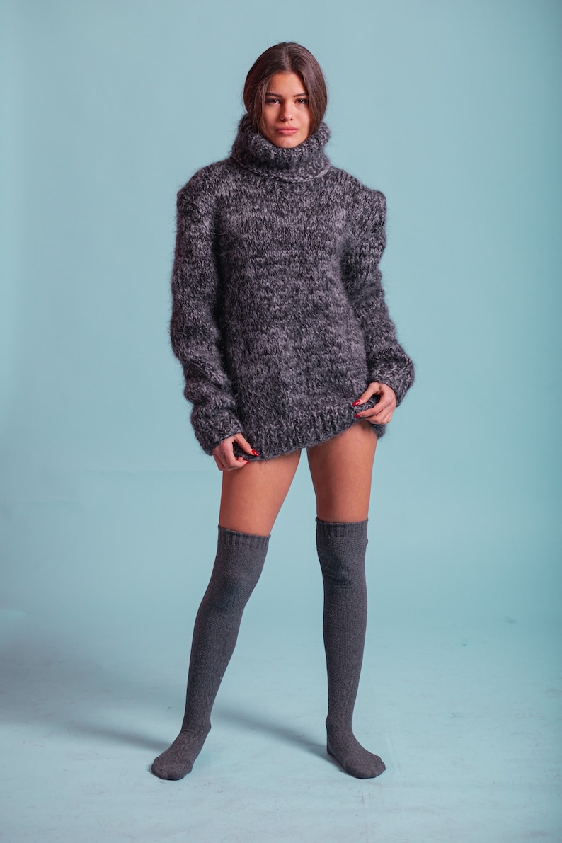 May include: A woman wearing a gray fuzzy turtleneck sweater and gray knee-high socks.