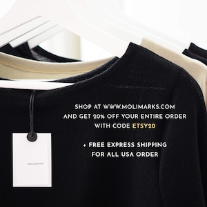 May include: Close-up of black, beige, and black crew neck shirts hanging on white hangers. A white tag with the brand name "MOLI MARKS" is attached to the black shirt. The text "SHOP AT WWW.MOLIMARKS.COM" is visible.