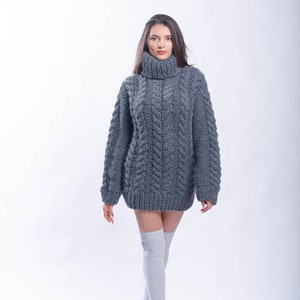 May include: A gray oversized cable knit sweater with a turtleneck.