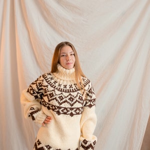 May include: A white and brown knitted sweater with a geometric pattern. The sweater has a turtleneck and long sleeves.