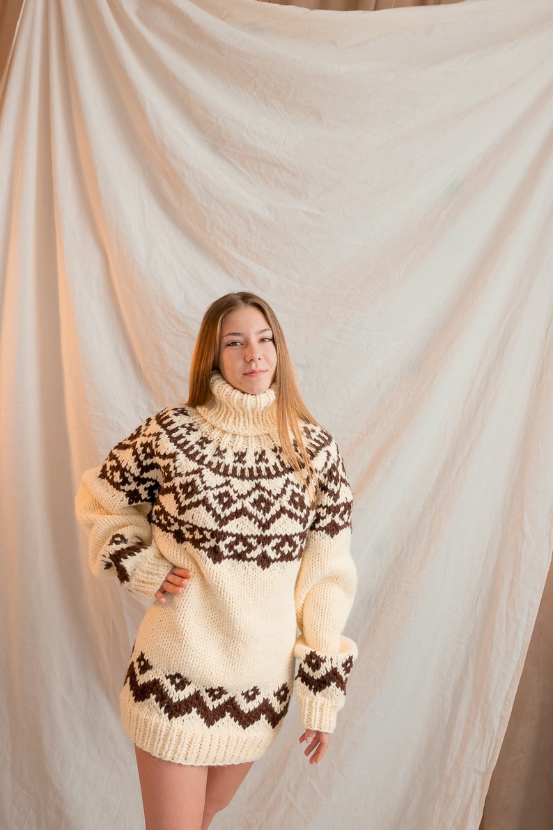 May include: A white and brown knitted sweater with a geometric pattern. The sweater has a turtleneck and long sleeves.