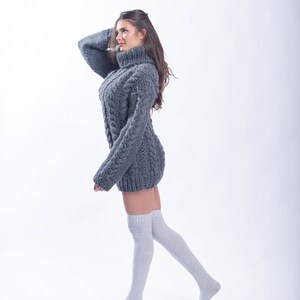 May include: A woman wearing a gray cable knit sweater dress and white knee-high socks.