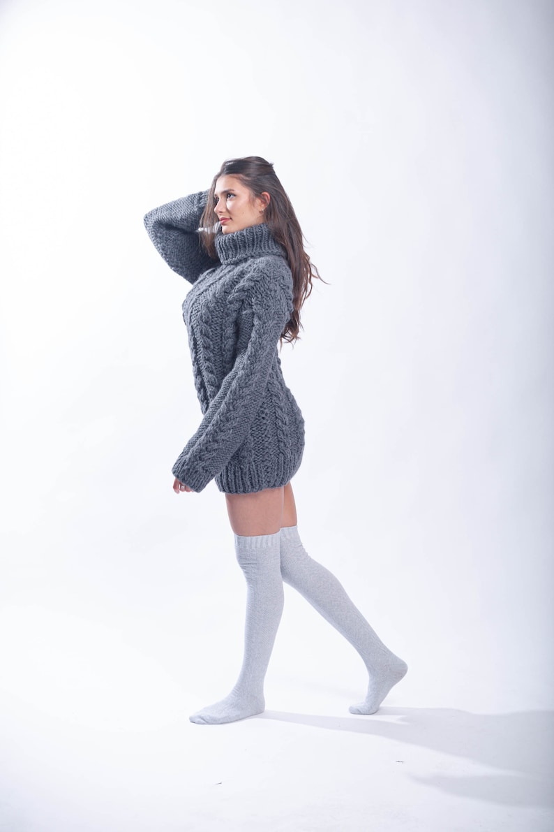 May include: A woman wearing a gray cable knit sweater dress and white knee-high socks.